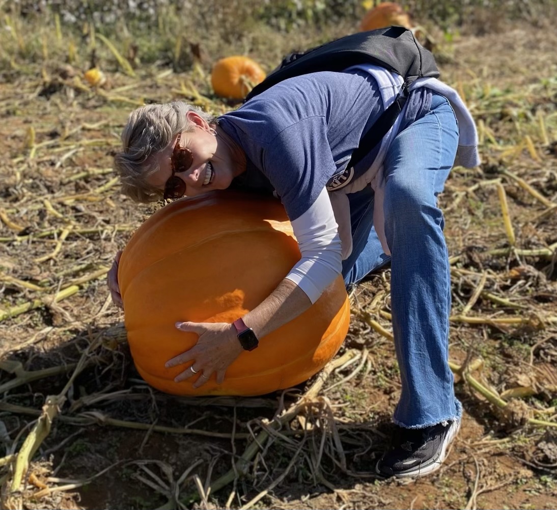 picture of rebecca recke picking up a large pumpkin